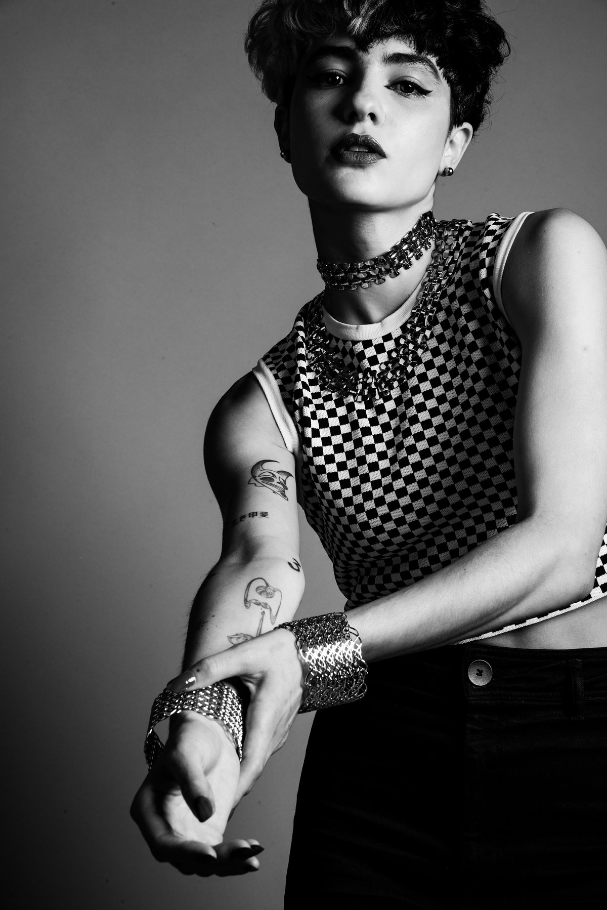 Black-and-white image of a model in a checkerboard top and bracelets