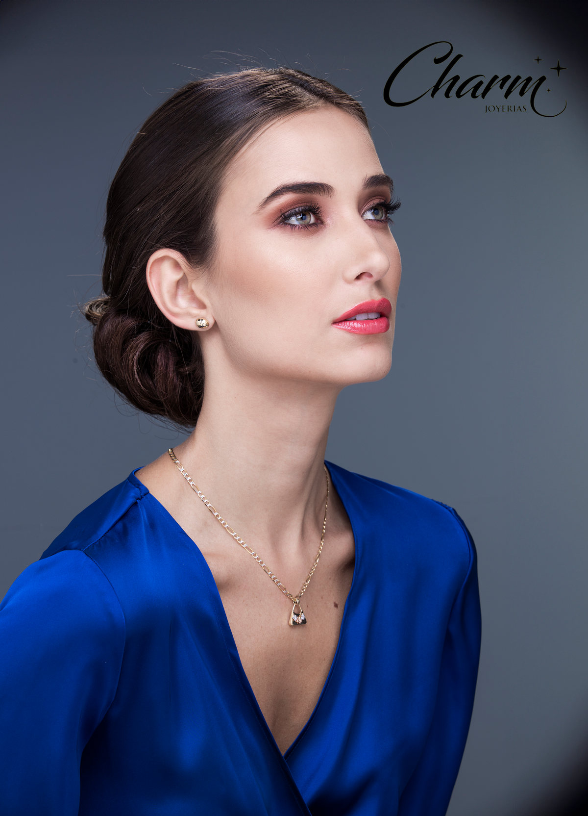 Retrato de modelo con blusa azul rey, peinado recogido y collar fino, con logotipo de Charm