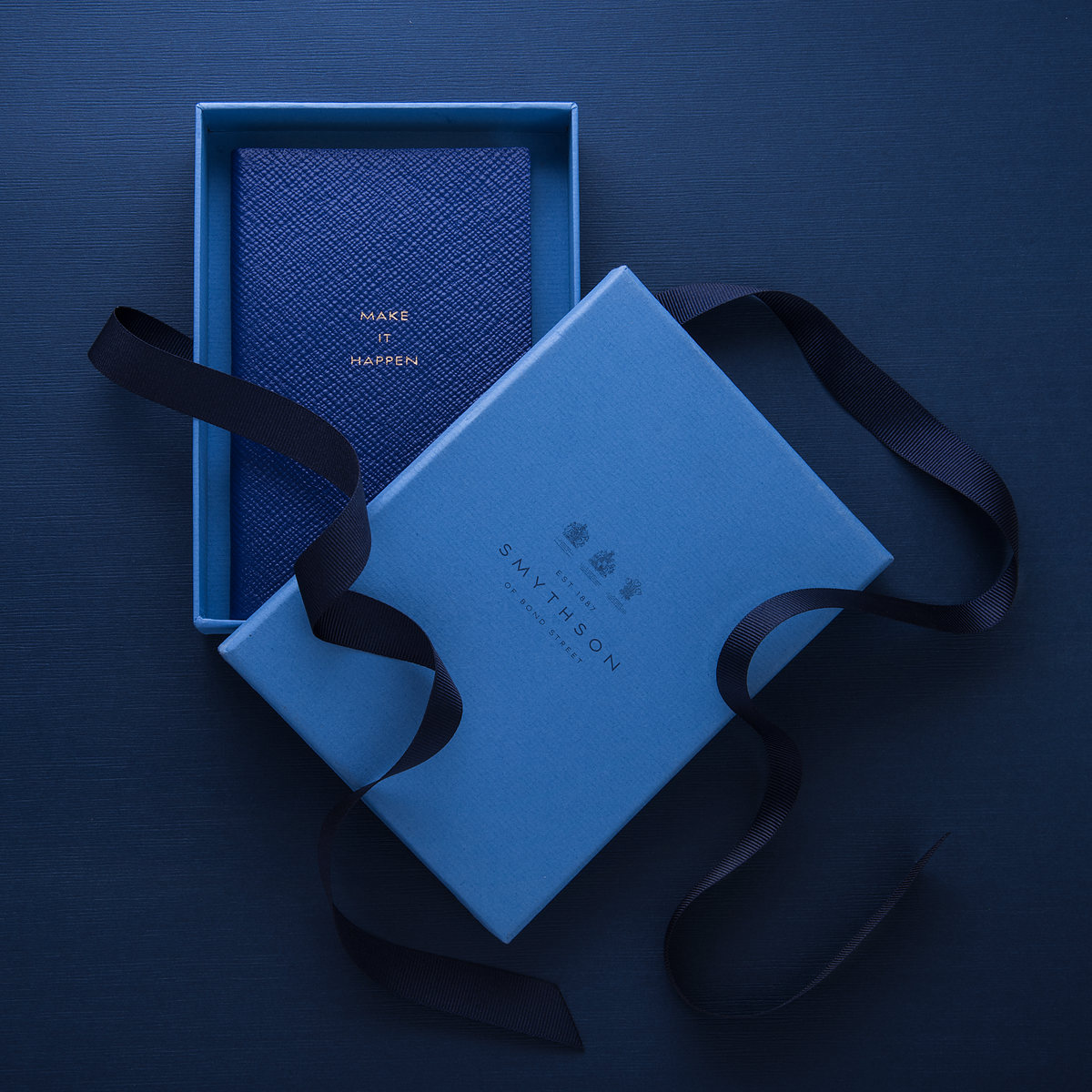 Libreta y caja azul Smythson con listón marino sobre fondo azul