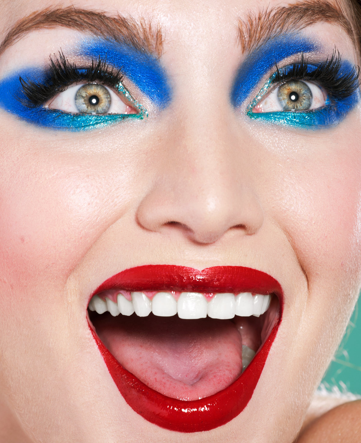Close-up of a laughing model with vivid blue eyeshadow and red lips