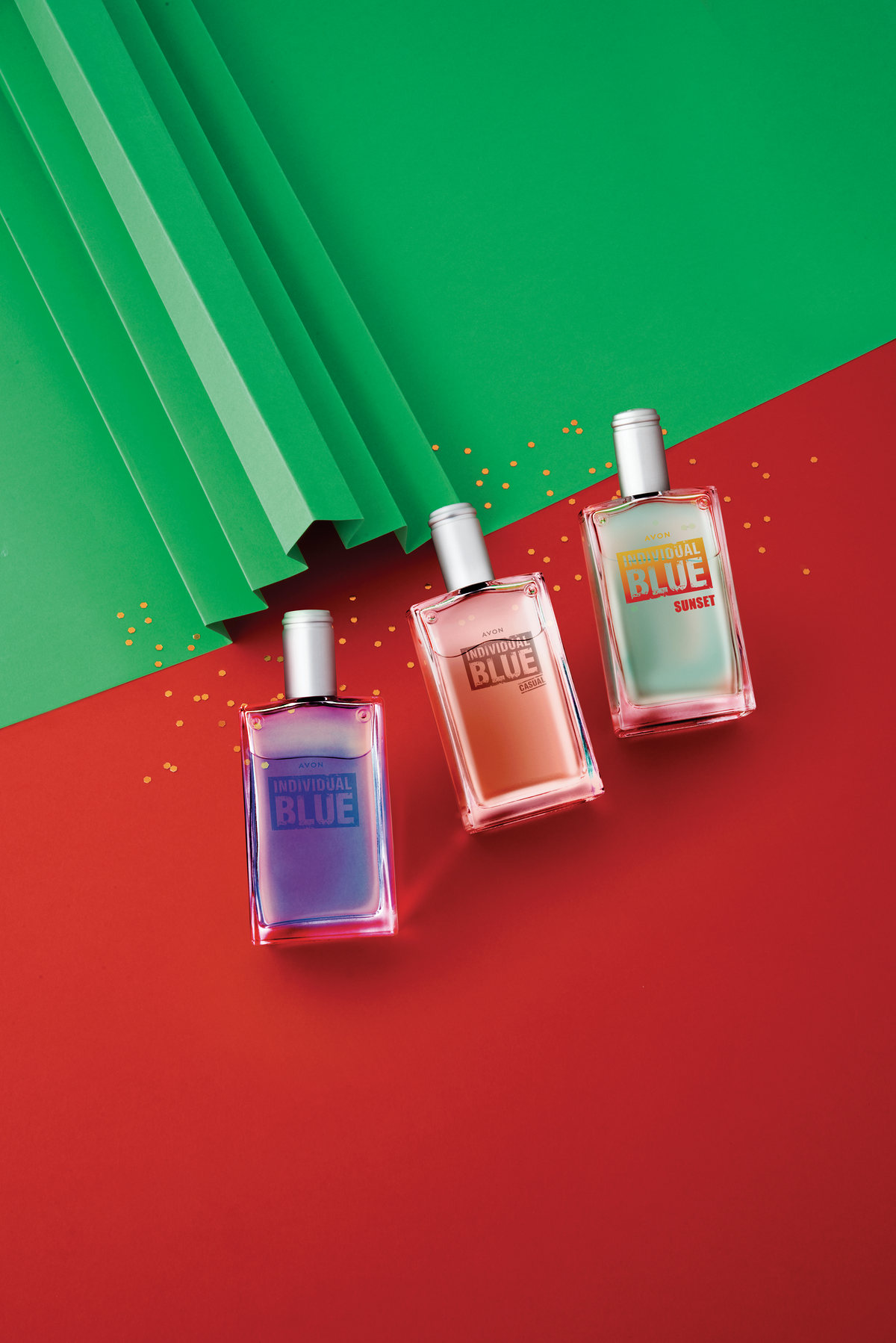Three fragrance bottles on red and green pleated paper