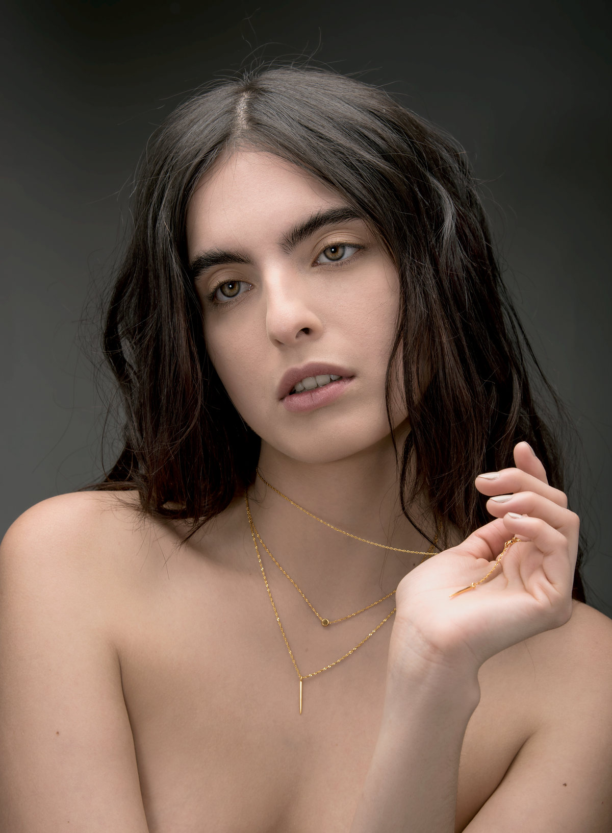 Portrait of a dark-haired model wearing fine gold necklaces