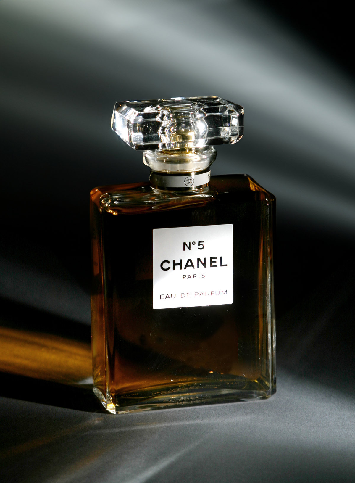 Chanel N°5 perfume bottle on a dark gray background with streaks of light