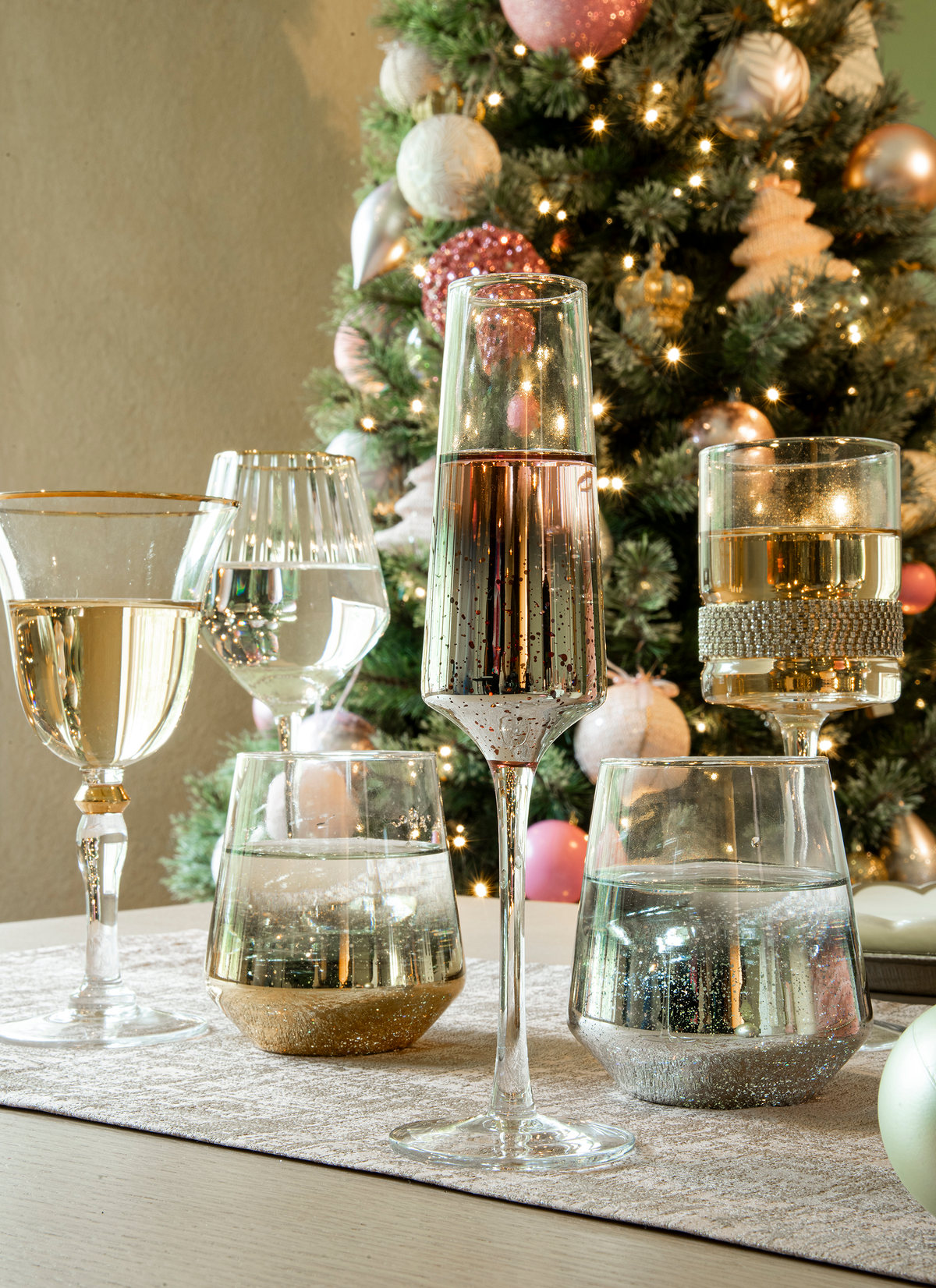 Crystal glasses with gold details on a table in front of a Christmas tree