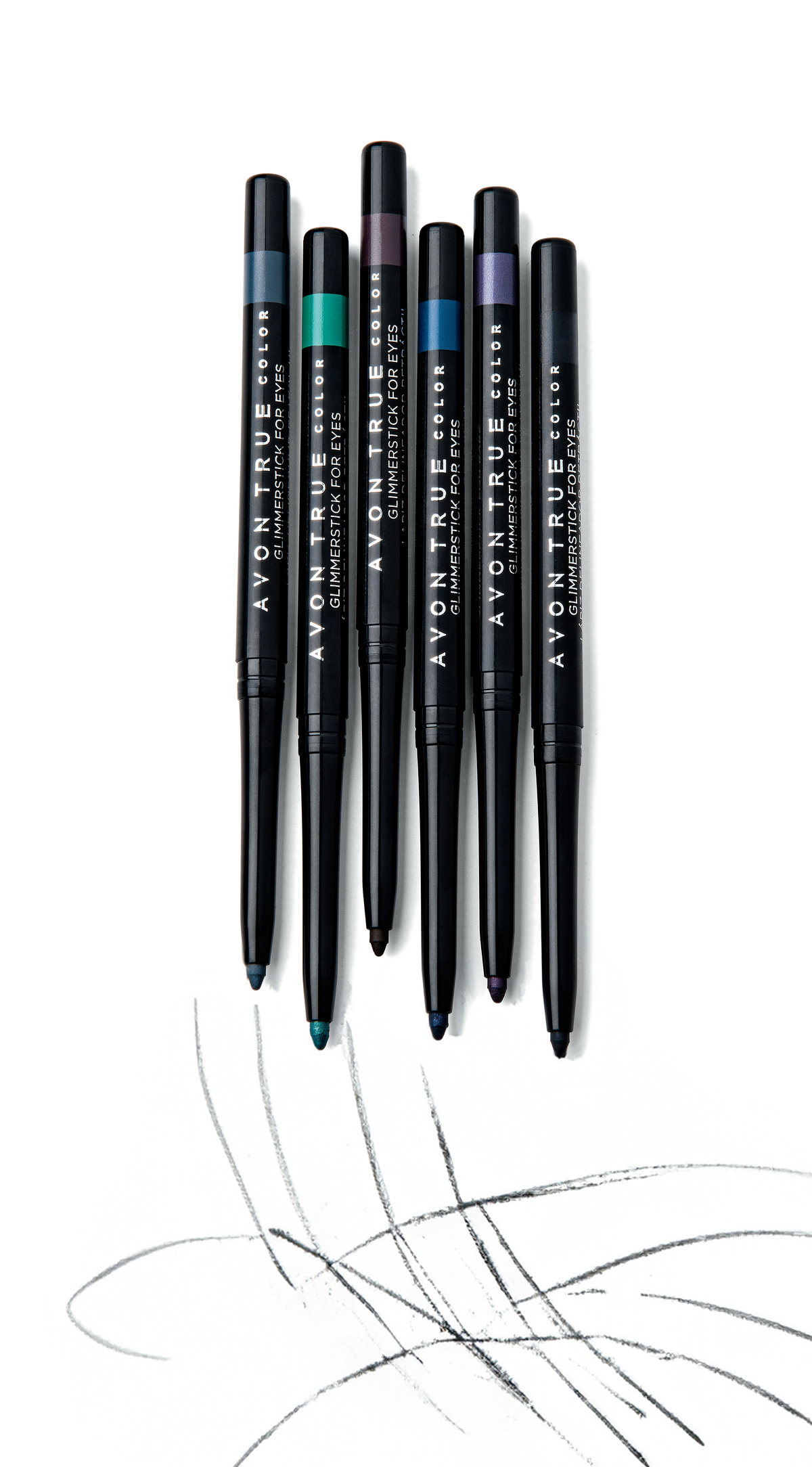 Black eyeliner pencils standing over graphite scribbles on white