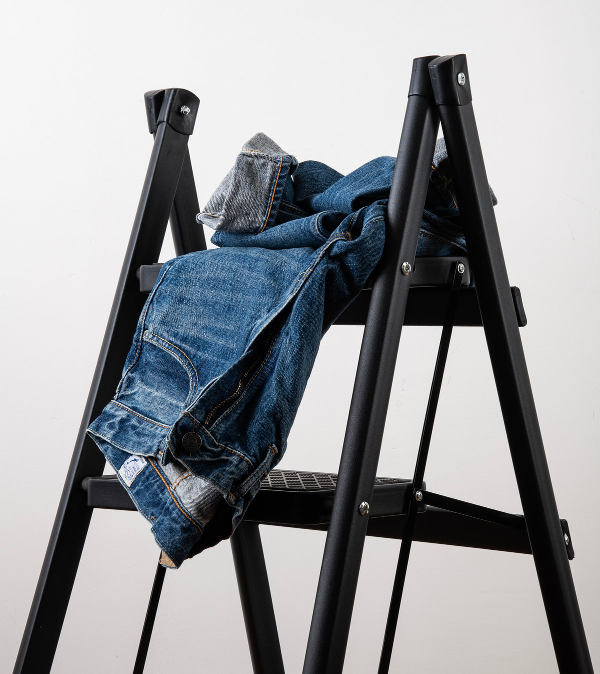 Jeans y chamarra de mezclilla colgados de una escalera negra