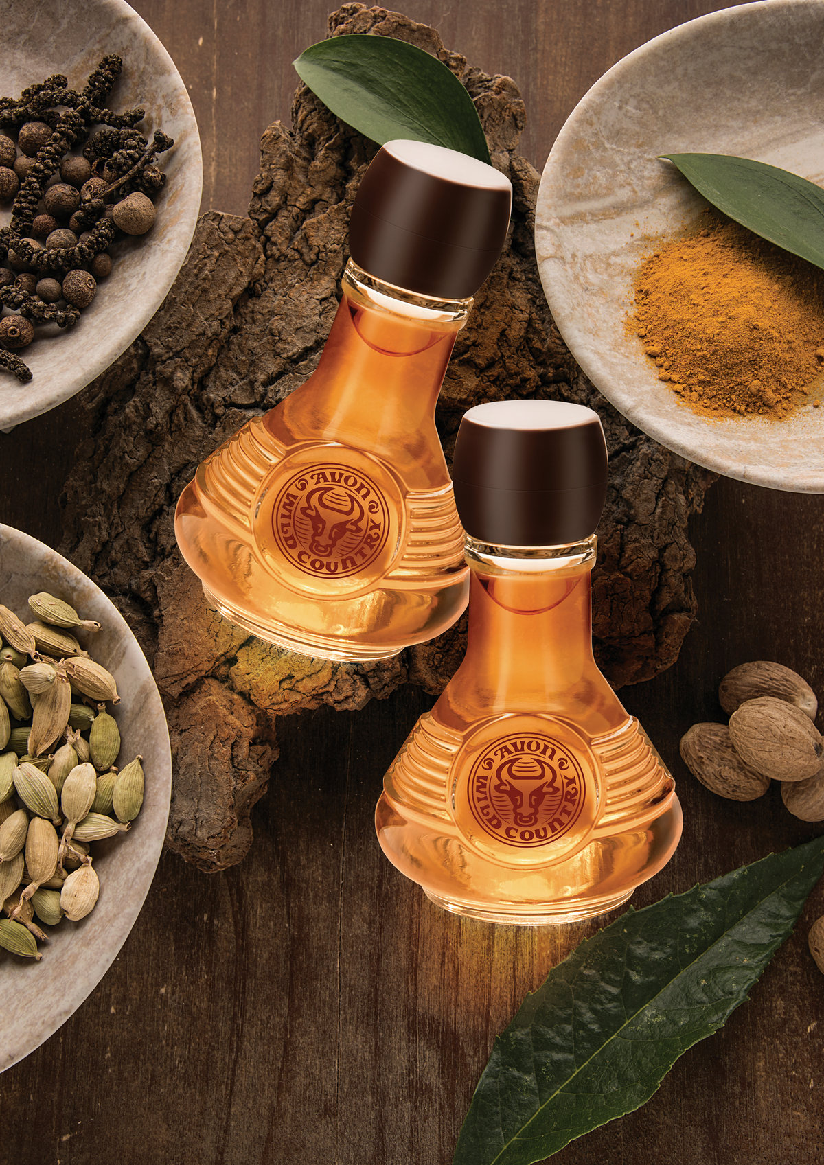 Amber fragrance bottles among bowls of spices on wood
