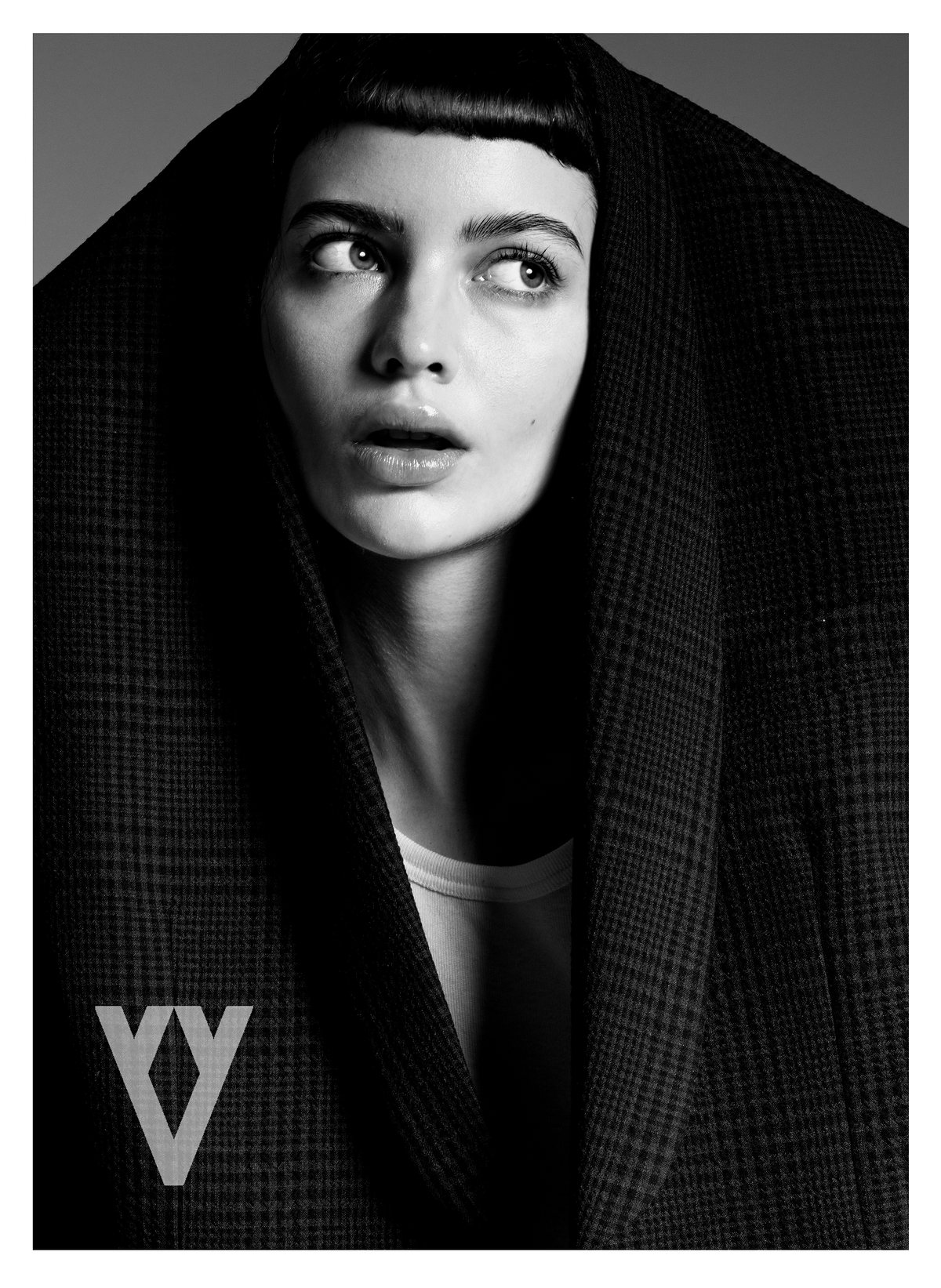 Retrato en blanco y negro de modelo con flequillo, envuelta en un abrigo oscuro, con logotipo de The Silver Deer