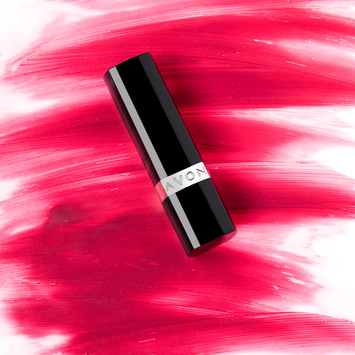 Black lipstick case lying on a fuchsia paint stroke