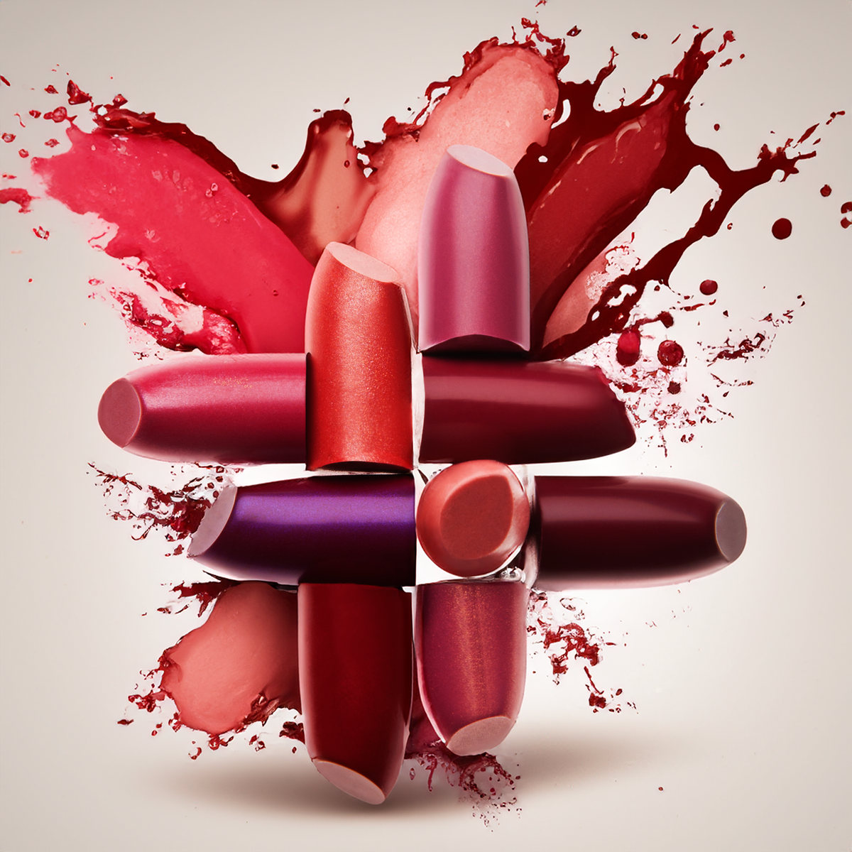 Red and plum lipsticks crossed over a red paint splash on a light background