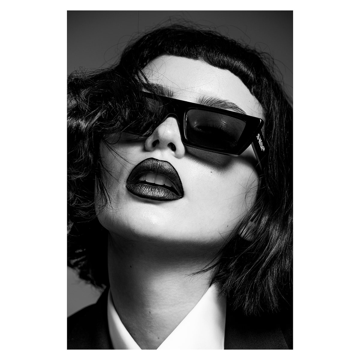 Black-and-white portrait of a model in dark sunglasses and dark lipstick