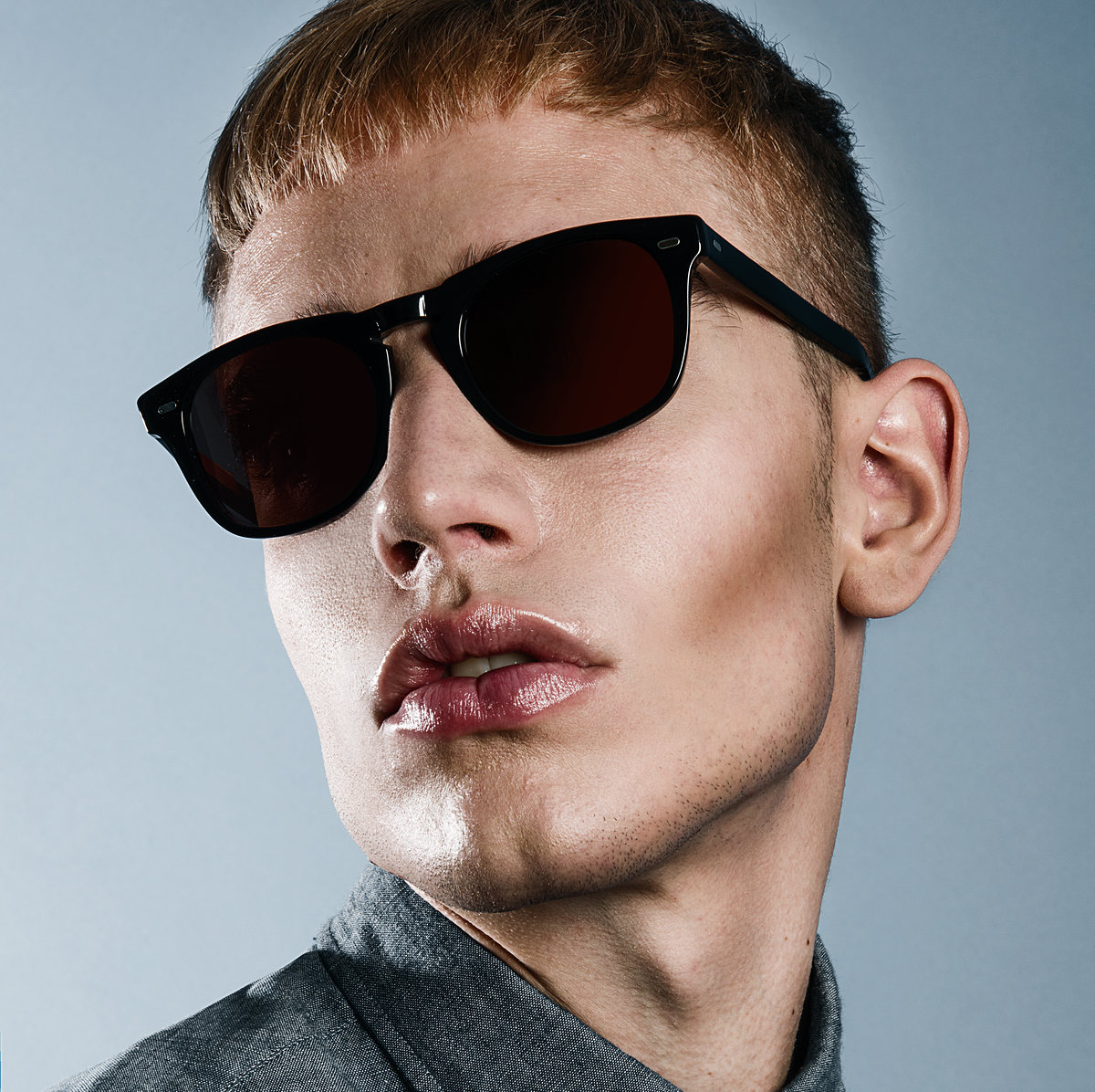 Primer plano de modelo con lentes oscuros sobre fondo azul