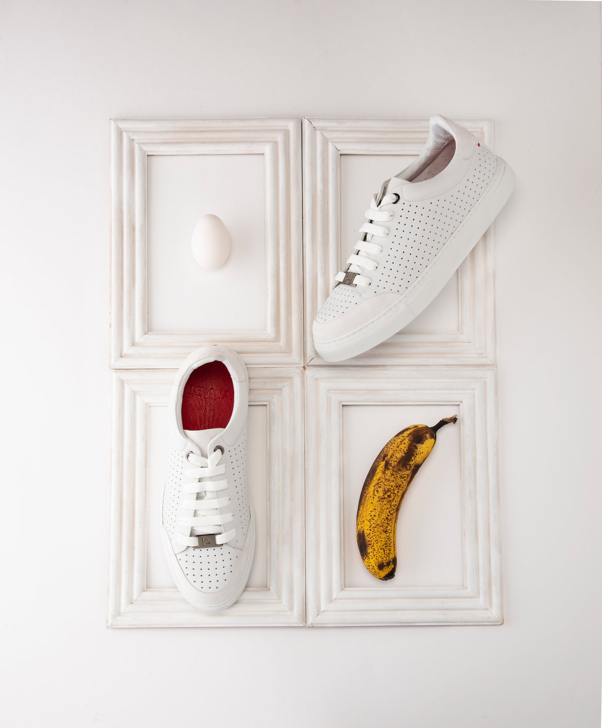 Tenis blancos dentro de marcos blancos junto a un huevo y un plátano