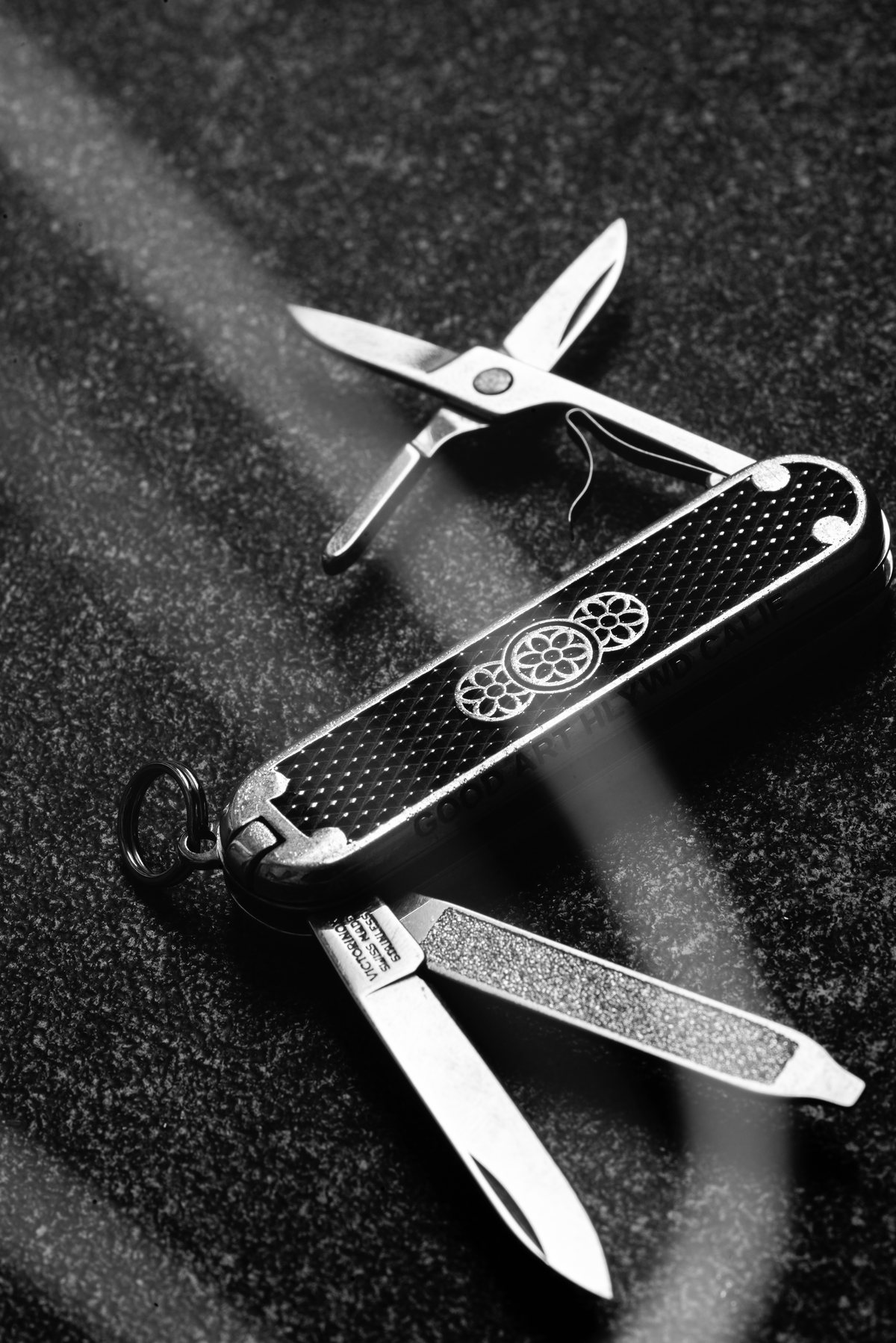 Navaja multiusos con tijeras abiertas, en blanco y negro sobre textura oscura
