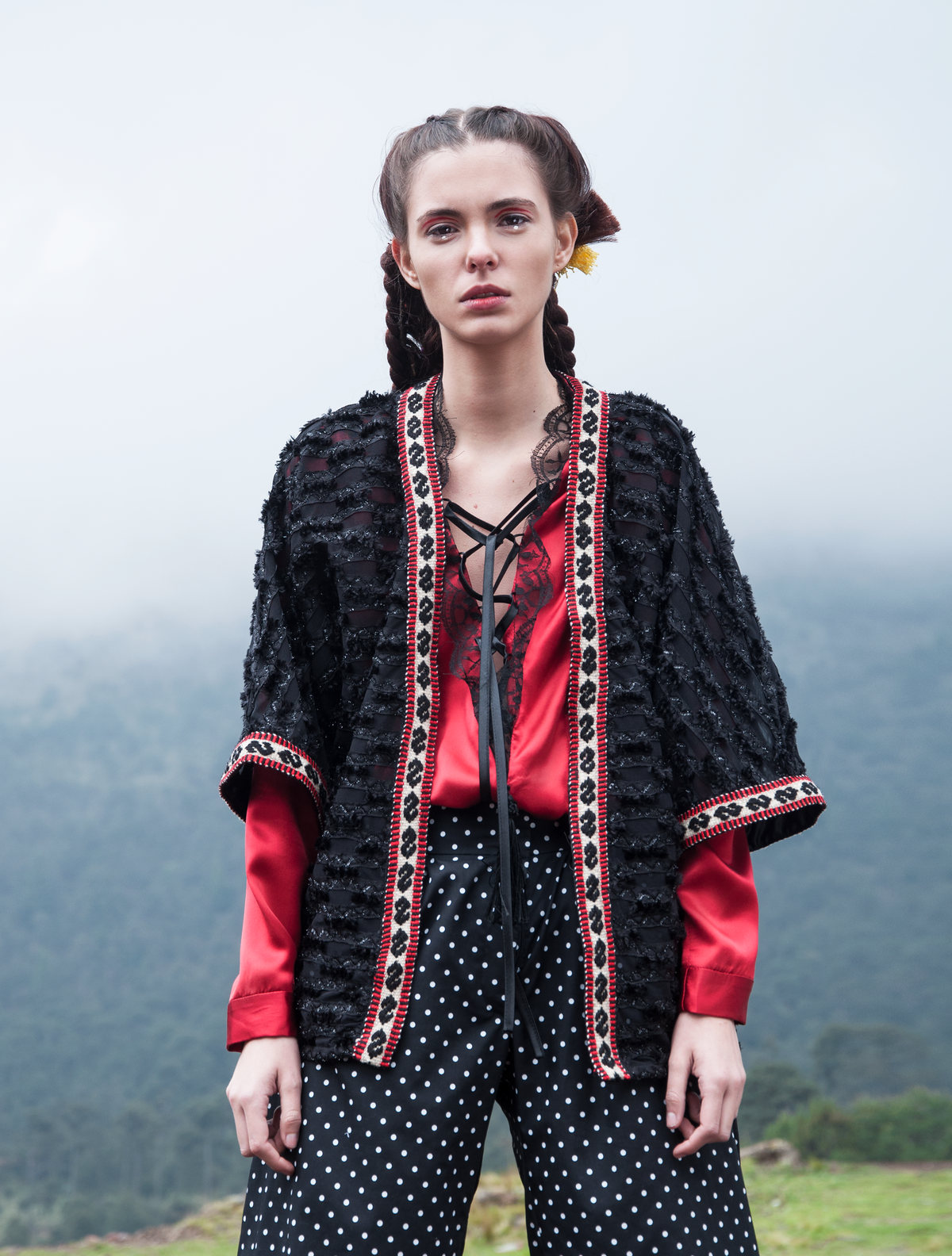 Modelo con chaqueta tejida en rojo y negro en un campo con niebla