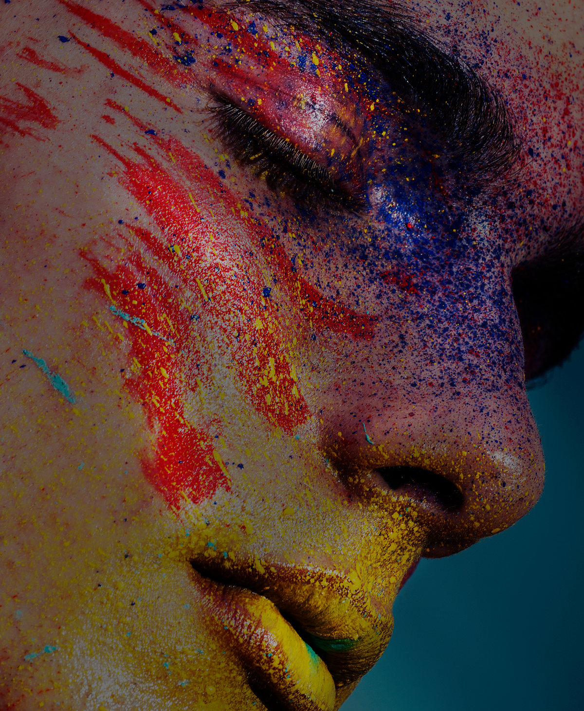 Profile of a face covered in red, blue and yellow pigment