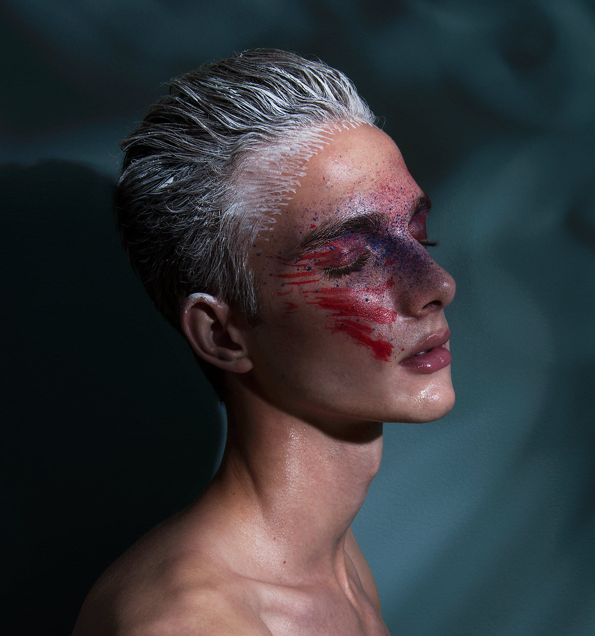 Profile of a model with slicked silver hair and red streaks across the face