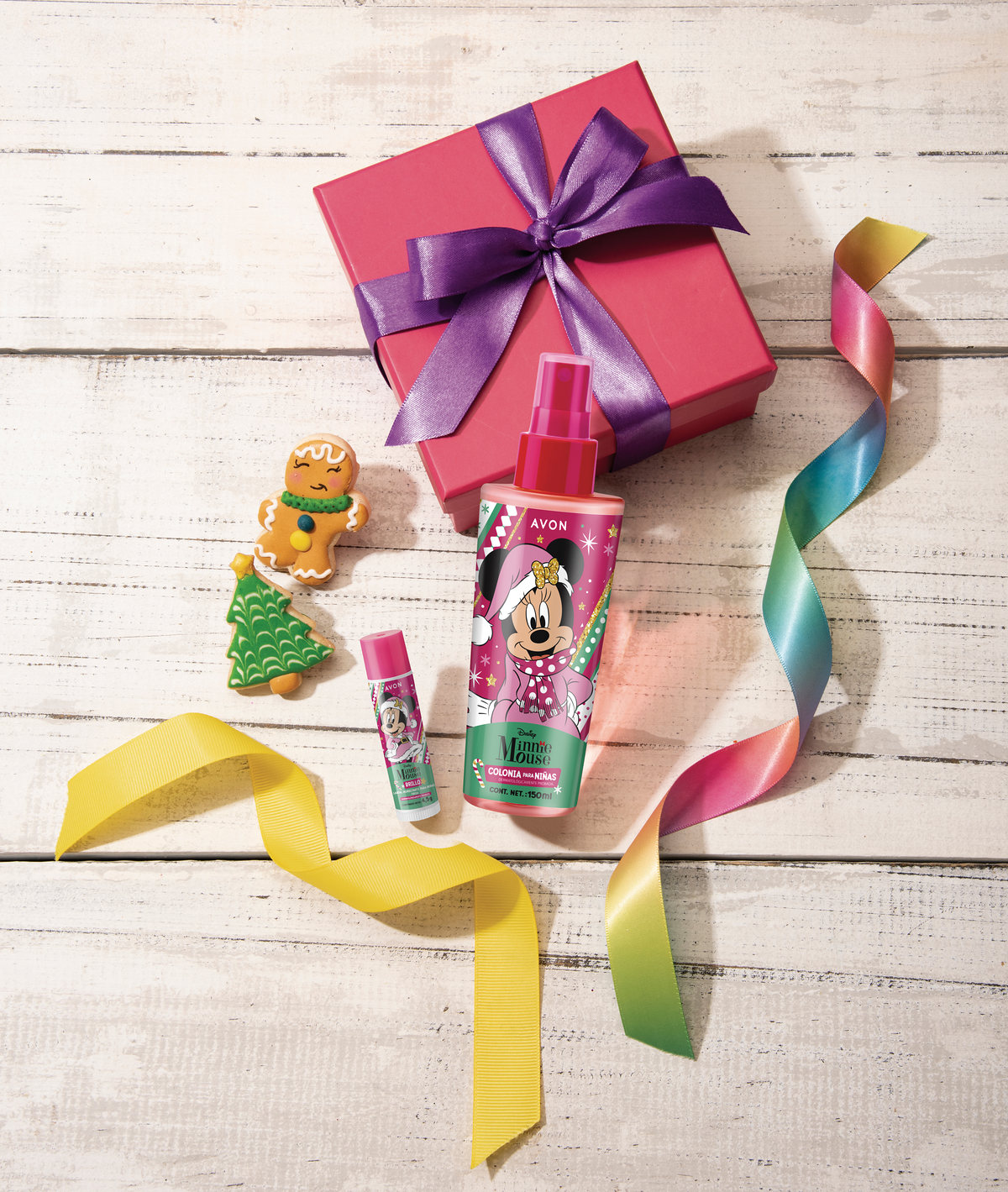 Gift box with colorful ribbons and a kids' body mist on white wood