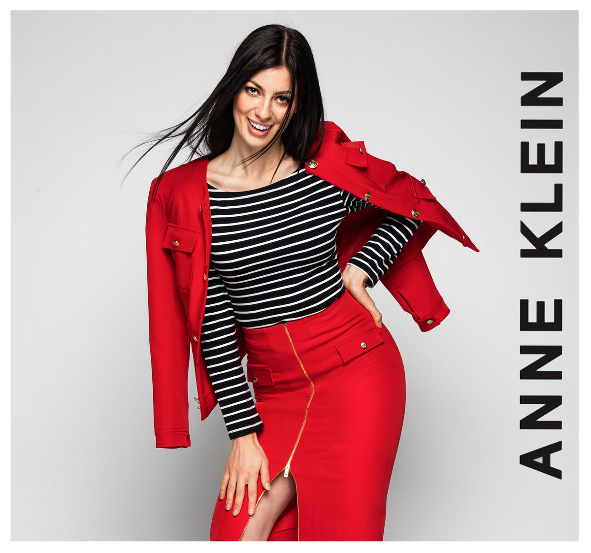 Modelo con chaqueta roja, blusa a rayas y falda roja, con logotipo de Anne Klein