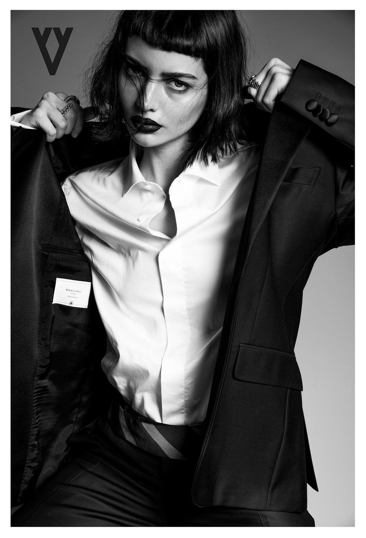 Retrato en blanco y negro de modelo con camisa blanca y saco negro, con logotipo de The Silver Deer