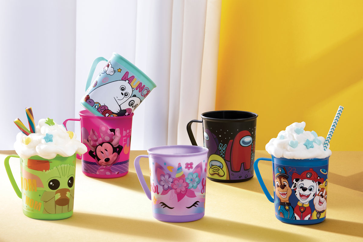 Kids' mugs topped with whipped cream by a window