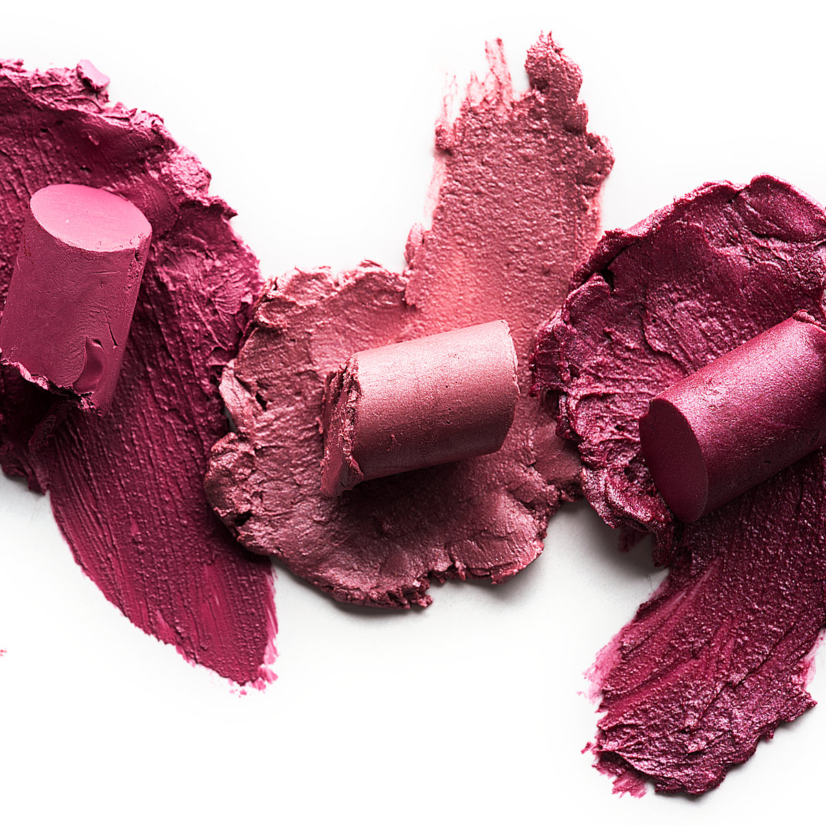 Pink and mauve lipsticks smeared on white
